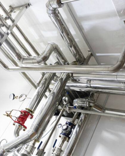 RVS-waterleidingen voor industriële warmteterugwinning geïnstalleerd aan het plafond van een technische ruimte.