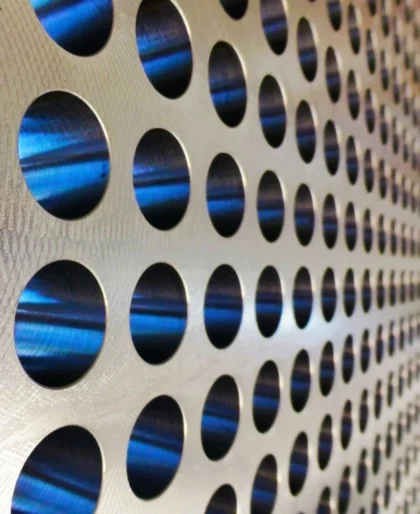 Close-up van een metalen warmtewisselaarplaat met perfect geboorde ronde openingen en blauwe accenten in de buizen.