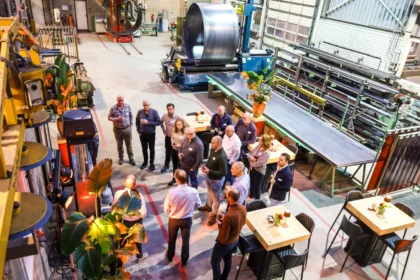 Groep deelnemers aan seminar over duurzaam bakken verzameld in een industriële werkplaatsomgeving.