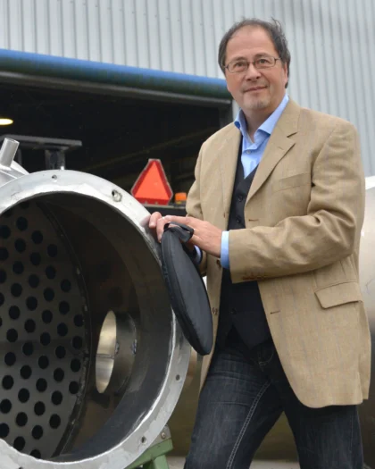 Man in colbert bij industriële installatie, symbool voor certificering en kwaliteitsborging door IMC Consultants.